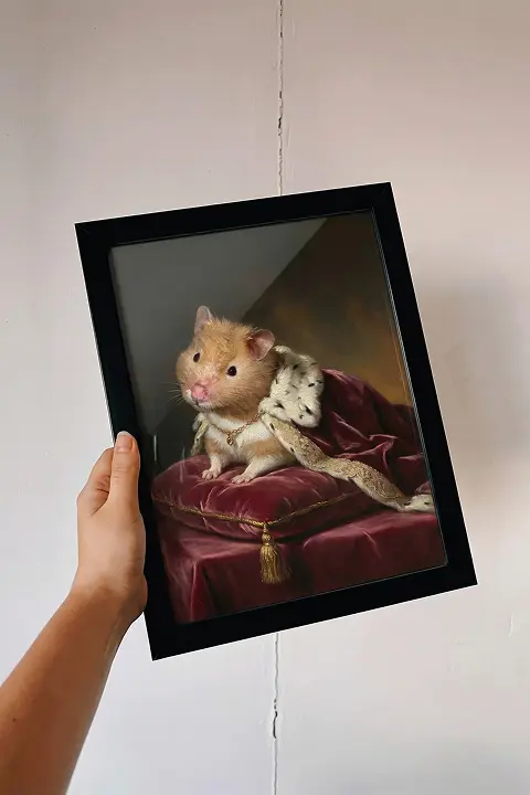 Mano sosteniendo retrato enmarcado de hámster con capa real estilo renacentista